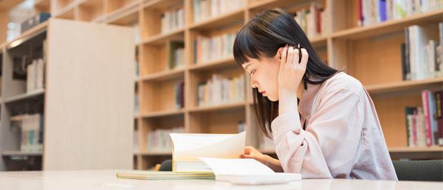 a Carroll University student sitting at a desk reading a book.